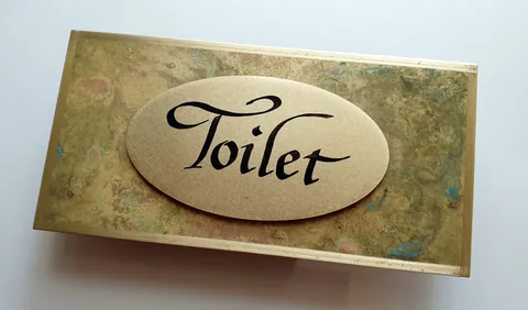 fancy brass toilet sign